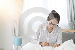 Asain woman writing on bed