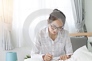 Asain woman writing on bed