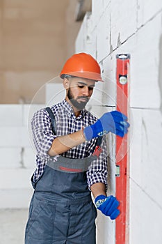 Asain worker using water level meter measuring the wall builder working with autoclaved aerated concrete blocks