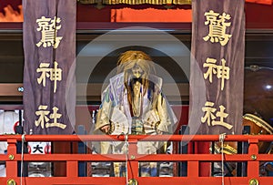 Japanese dancer in kimono dancing with an eagle mask in Ootori shrine during the Tori-no-Ichi fair.