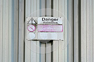 Asbestos danger sign on old galvanised shed wall.