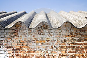 Asbestos roof above an old brick wall