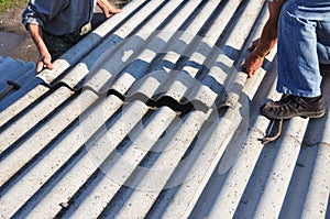 Asbestos roofing construction. Roofers installing asbestos roof sheets