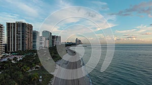 ascending aerial footage of the coast of the Atlantic ocean with hotels and luxury condominiums in the city skyline at sunrise