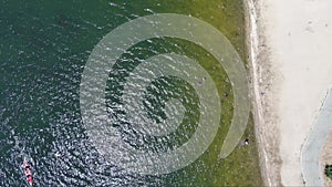 ascending aerial footage of the rippling blue waters of Silverwood Lake with a beach and people swimming in the water