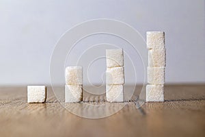 Ascending stacks of sugar cubes on wooden table