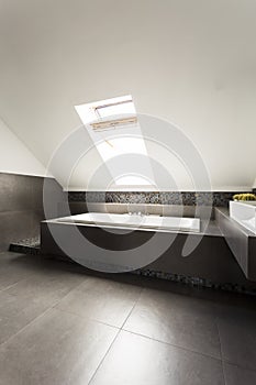 Ascetic attic bathroom with bathtub