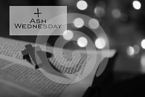 Ash Wednesday. Happy Ash Wednesday concept with wooden holy cross crucifix of Jesus Christ on open bible book page in black white.