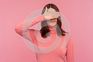 Ashamed confused woman with brown hair closing eyes with hand, hiding, ignoring dont want to see