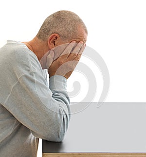 Ashamed and depressed man hiding his face with his hands by a table. Close-up image image  on white