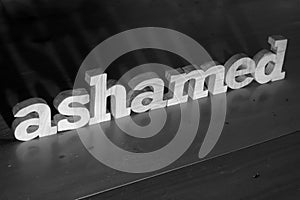 Ashamed, text words typography written with wooden letter on black background, life and business negativity