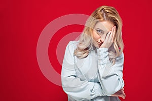 Ashamed woman covering face with hand. Shame, isolated on red background. Guilty girl