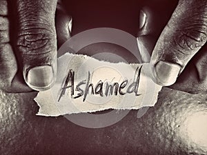 ashamed word on the dark grey color paper holding in hands