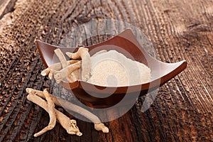 Ashwagandha powder in bowl with roots