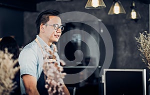 Asia Barista waiter smile and talking to customer in coffee shop,cafe owner at counter bar,Food and drink business concept,Service