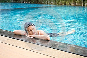 Asia beautiful Woman relaxing at the Edge of Swimming Pool