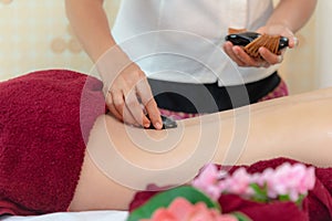 Asia beauty woman lying down on massage bed with traditional balinese hot stones along the spine at Thai spa and wellness center,