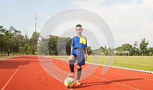 Asia boy playing Soccer football field stadium.