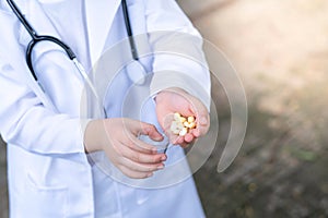 Asia boy wearing a medical suite and place doctor stethoscope on his neck. A boy pouring some drugs on his hand to a small cup.