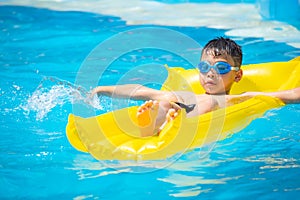 Asia boy wearing swimming goggles on yellow protrude in a swimming pool photo