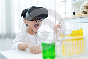 Asia boy wearing VR and pouring solution from test tube into flask in the laboratory at home..Colorful of liquid in the beaker and