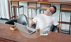 asia casual man sit back feel tired from work at laptop in coffee shop,stress business concept,work outside office,work at home.