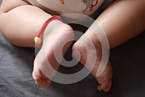 Close-up body parts baby infant chubby feet foot toes on golden ankle chain black isolated background innocent pure happy smile