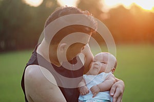 Asia Chinese happy Dad hug hold new-born chubby baby son in park forest outdoor in summer love peace smile bathed in sun portrait