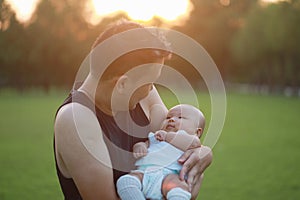 Asia Chinese happy Dad hug hold new-born chubby baby son in park forest outdoor in summer love peace smile bathed in sun portrait