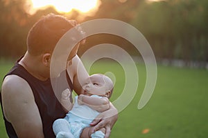 Asia Chinese happy Dad hug hold new-born chubby baby son in park forest outdoor in summer love peace smile bathed in sun portrait