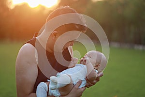 Asia Chinese happy Dad hug hold new-born chubby baby son in park forest outdoor in summer love peace smile bathed in sun portrait