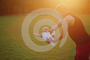 Asia Chinese happy Dad hug hold new-born chubby baby son in park forest outdoor in summer love peace smile bathed in sun portrait