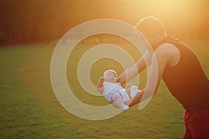 Asia Chinese happy Dad hug hold new-born chubby baby son in park forest outdoor in summer love peace smile bathed in sun portrait