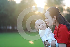 Asia Chinese happy mom hug hold kiss new-born chubby baby park forest outdoor in summer love peace smile bathed in sun portrait