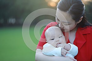 Asia Chinese happy mom hug hold kiss new-born chubby baby park forest outdoor in summer love peace smile bathed in sun portrait