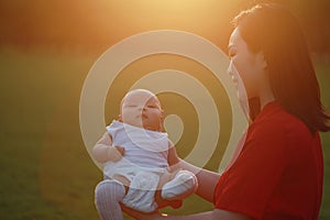 Asia Chinese happy mom hug hold kiss new-born chubby baby park forest outdoor in summer love peace smile bathed in sun portrait