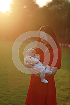 Asia Chinese happy mom hug hold kiss new-born chubby baby park forest outdoor in summer love peace smile bathed in sun portrait