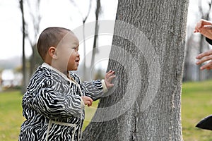 Asia Chinese little baby toddler boy child play hide and seek with his mom mother outdoor sunny happy smile carefree flower meadow