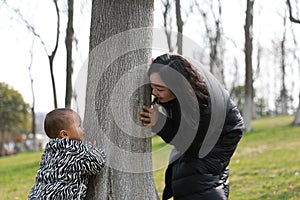 Asia Chinese little baby toddler boy child play hide and seek with his mom mother outdoor sunny happy smile carefree flower meadow