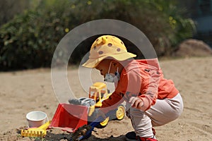 Asia Chinese little baby toddler boy child play sand at beach tool toy cars buckets and spades outdoor sunny happy carefree spring