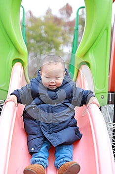 Asia Chinese little baby toddler boy child play slide outdoor have fun amusement park happy carefree winter casual joyful