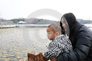 Asia Chinese Mom Mother and son maternal love hug embrace pond outdoor in park forest winter sunny day happy smile carefree cold