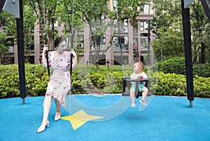 Asia Chinese woman and toddler baby boy son sit on swing play games have fun outdoor sunny day in Summer maternal love family
