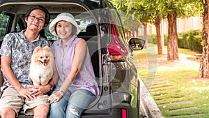 Asia couple family with lovely puppy pomeranian dog at the back of suv car on travel tip and copy space