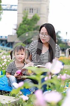 Asia cute laugh lovely adorable girl read book with mother enjoy free day with mom tell story outdoor in summer park happy smile