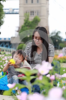 Asia cute naughty lovely adorable girl read book with mother enjoy free day with mom tell story outdoor in summer park happy smile
