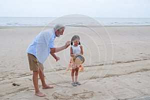 asia cute small girl and caucasian old man relaxing on the beach