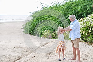 asia cute small girl and caucasian old man relaxing on the beach