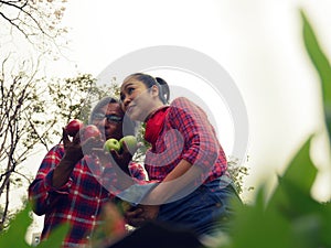 Asia family lover smile portrait and holding red apple in garden park.