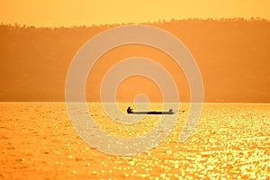 Asia fisherman on wooden boat sunset or sunrise in the river - Silhouette fisherman boat with mountain island background on the